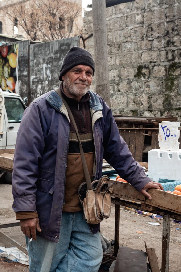 Bearded elderly man leaning on a wooden cart in a street of Latakia, Syria.