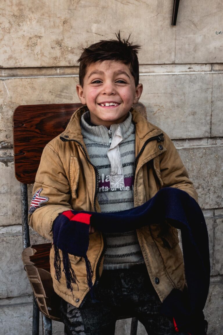 : Portrait of a smiling young boy sitting and holding a toy in Aleppo, Syria.