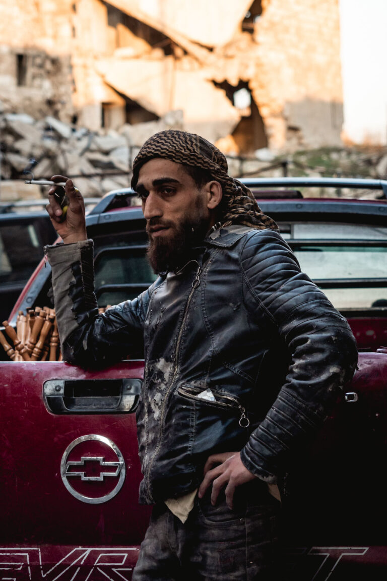Young man with a piercing gaze leaning against a car in a street in Aleppo, Syria.