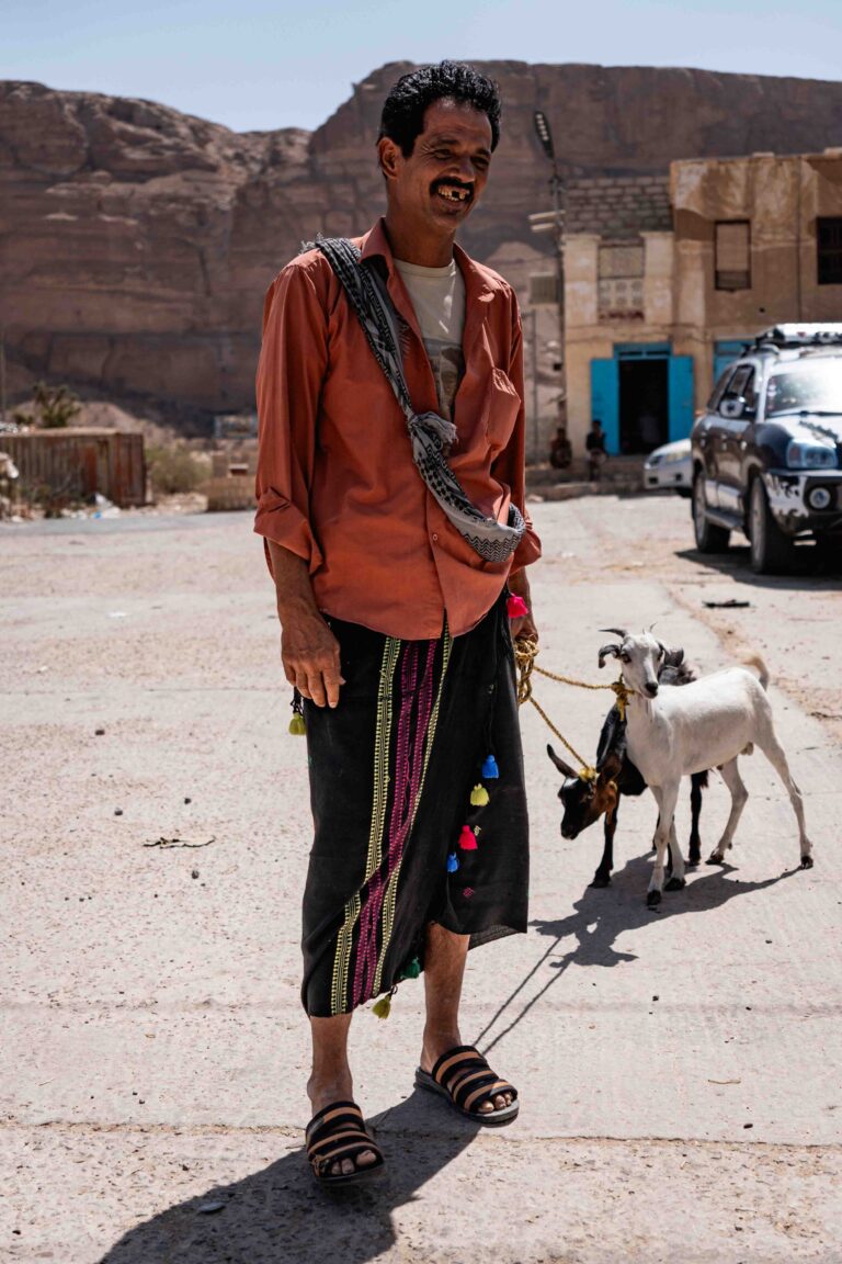 A man standing with two goats in the village of Budah, Yemen.