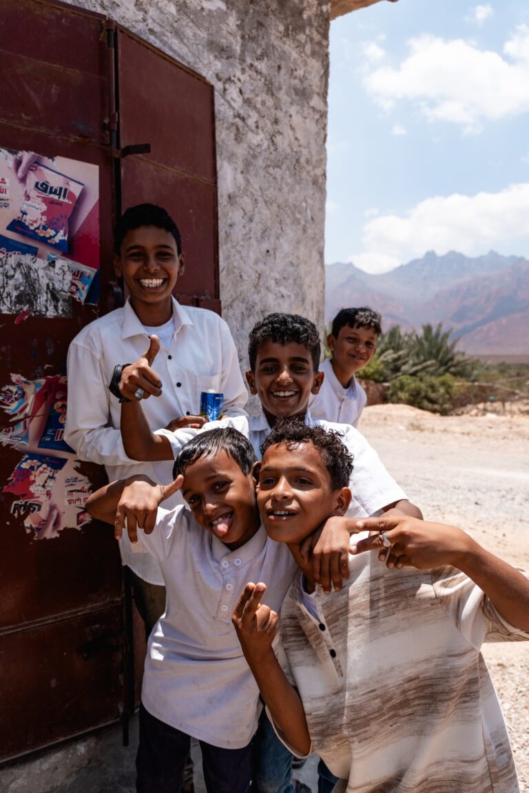 A group of cheerful, smiling children posing together outdoors on Socotra Island.