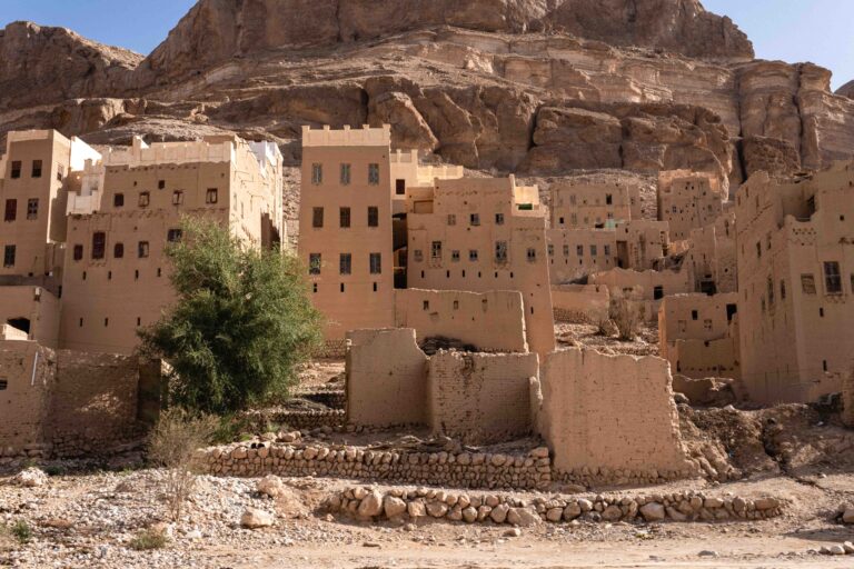 Panoramic view of an ancient mud-brick village nestled against a rocky desert cliffside